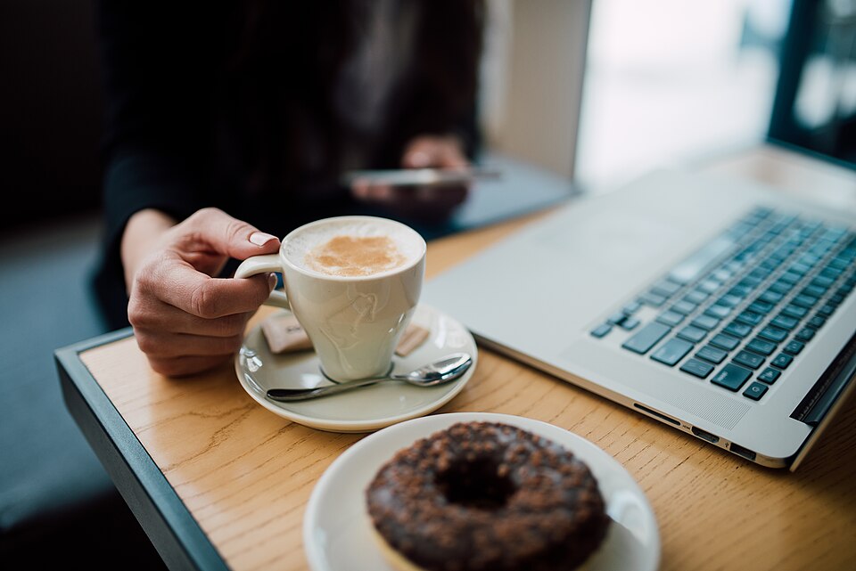 A person with a laptop and coffee browsing on their own