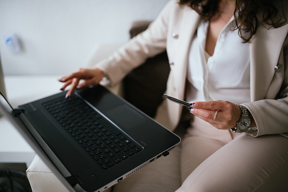 A person shopping online on a laptop with a card in hand