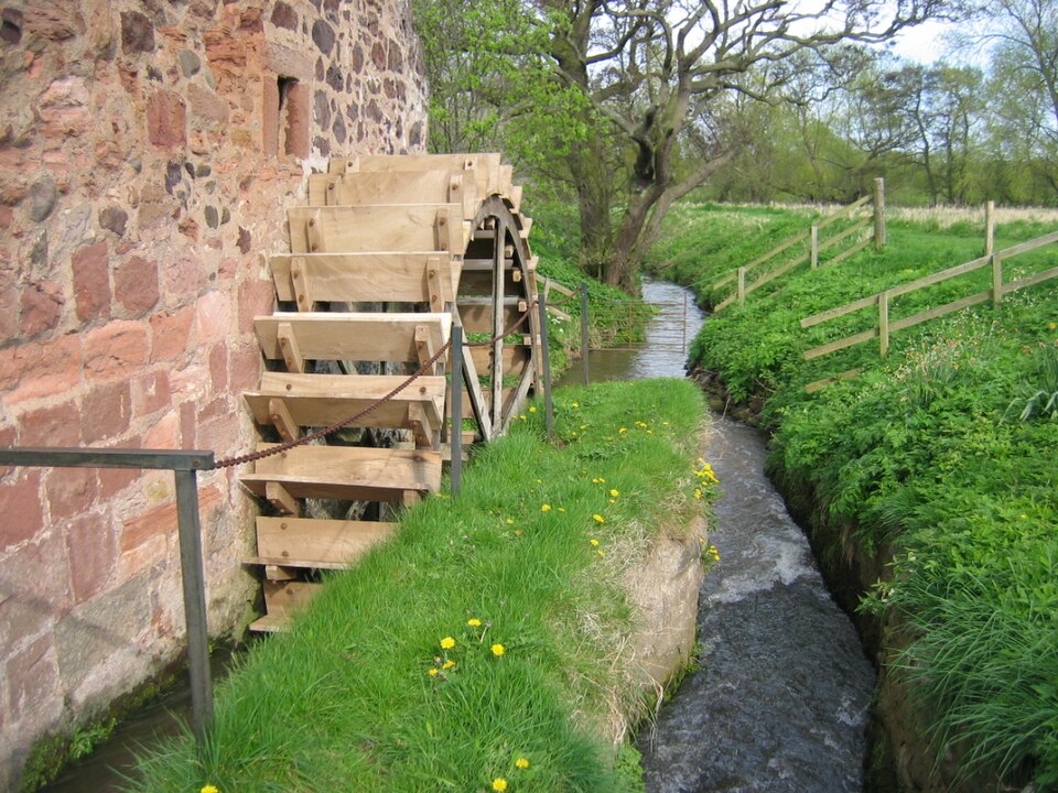 A wooden water wheel beside a stone mill